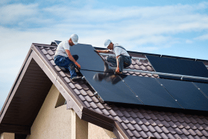 Two men installing solar panels on a roof